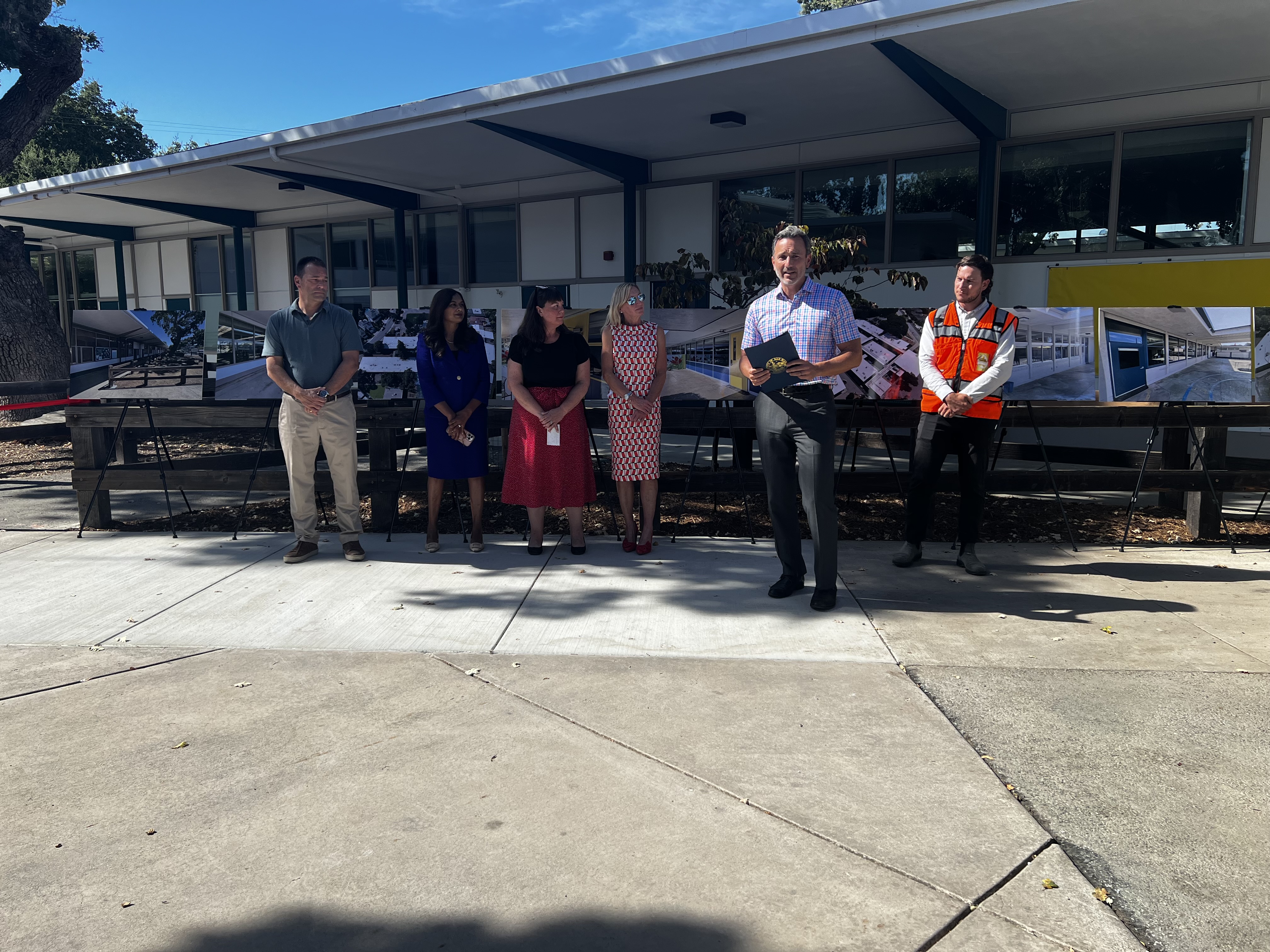 Ribbon cutting ceremony speakers outside a modernized school campus